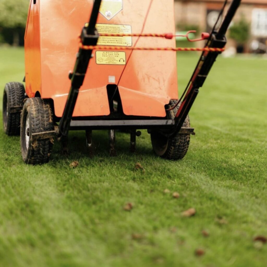 Core aerator moving across healthy grass