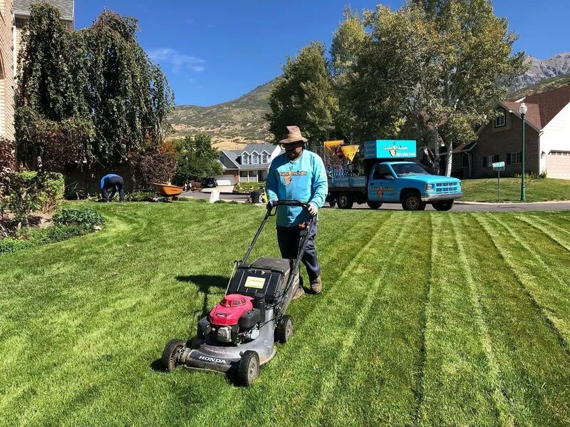 Technician mowing a striped residential lawn